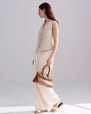 Side full-body view of model in neutral outfit carrying the Silkyhaus brown patterned top-handle handbag with gold hardware