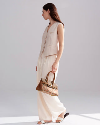 Side full-body view of model in neutral outfit carrying the Silkyhaus brown patterned top-handle handbag with gold hardware