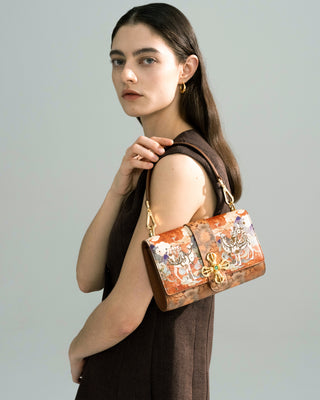 Silkyhaus side half-body view of female model carrying the brown embroidered leather handbag with gold hardware
