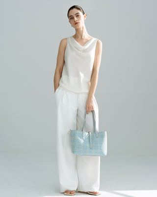 front full-body view of model in wihte outfit carrying the silkyhaus light blue patterned silk brocade & genuine leather tote bag with gold hardware