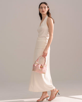 Silkyhaus pink brocade hobo bag with gold hardware, side full-body view of model in neutral outfit