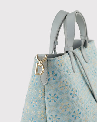 Close-up detail of Silkyhaus premium mulberry silk brocade fabric, showcasing intricate light blue traditional jacquard weave texture on the luxury tote bag