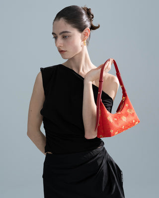 The model in black is holding the brocade leather hobo handbag in her left hand