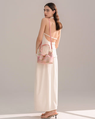 Model carrying the Silkyhaus pink brocade mini crossbody bag, shown in side half-body view with a white dress