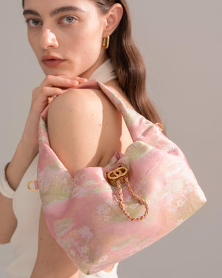 Close up half body view of model carrying Silkyhaus pink floral brocade mini bag with gold hardware