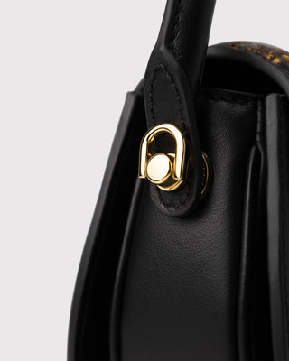 Close-up of hardware on black scroll pattern embroidered leather bag
