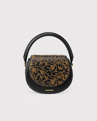 Front view of black scroll pattern embroidered top handle bag